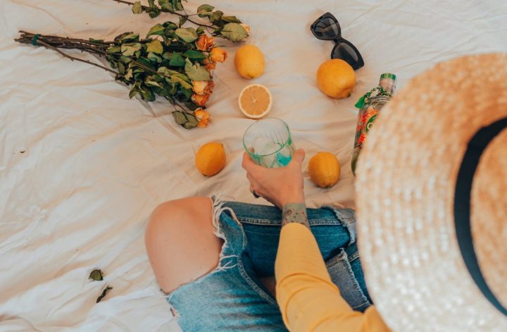 sitting on a picnic blanket with a straw hat