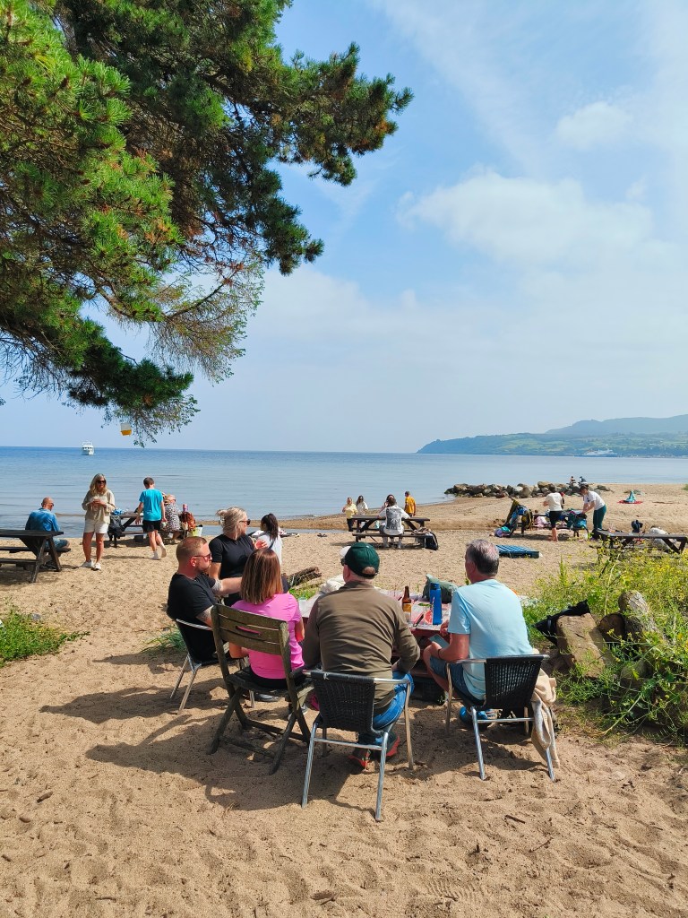 People having drinks in the beer garden on the beach on Arran.