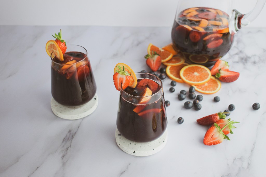 Red wine sangria in a jug and two glasses with fruit on the table